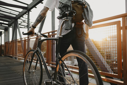 Radfahrer f&auml;hrt mit Singlespeed bei Sonnenuntergang durch die Stadt