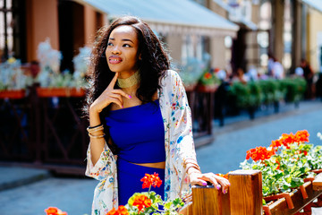 Portrait beautiful african woman in blue skirt and top posing over european city street background in summer.