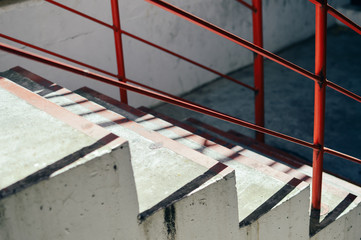 Light staircase with red handrails and concrete walls abstract background