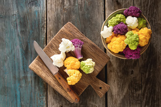 A rainbow of food. Purple cauliflower, orange cauliflower and broccoli, from the local market in London. Food for a vegan and a vegetarian. Dark background. Top view