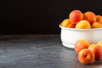 Ripe apricots in a bowl. Dark background. Food for a vegan and a