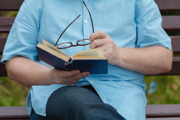 Man sitting on a bench reading a book.