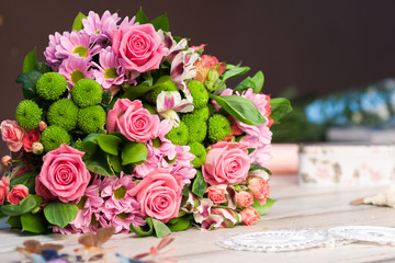 Bouquet of pink and red roses lies on a white wooden table, spase for text