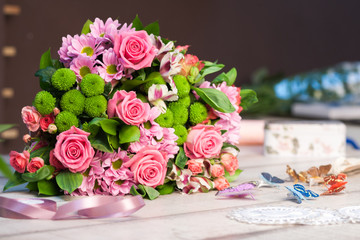 Bouquet of pink and red roses lies on a white wooden table, spase for text