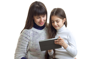 Portrait of a little girl with her mom who look at the Tablet