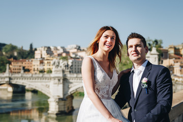 Bride and groom wedding poses on the bank of the river Tiber looking, Rome, Italy