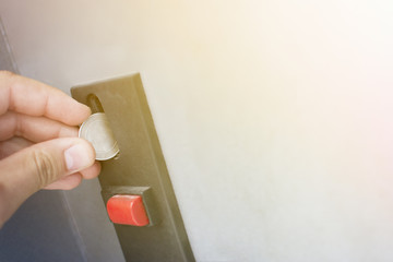 Close-up of human hand inserting coin in vending machine.