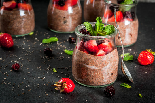Healthy vegan breakfast. Dessert. Alternative food. Pudding with chia seeds, fresh strawberries, blackberries and mint. On a dark stone background. Copy space