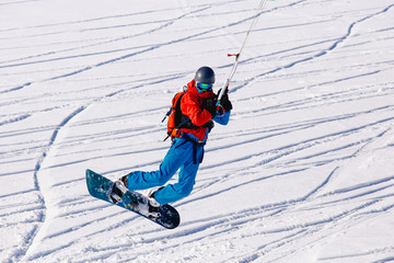 Fototapeta na wymiar Snowboarder with a kite on fresh snow in the winter in the tundra of Russia against a clear blue sky. Teriberka, Kola Peninsula, Russia. Concept of winter sports snowkite.
