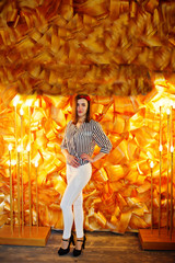 Naklejka premium Fashionably-dressed bridesmaid posing against decorative golden wall in the restaurant at bachelorette party.
