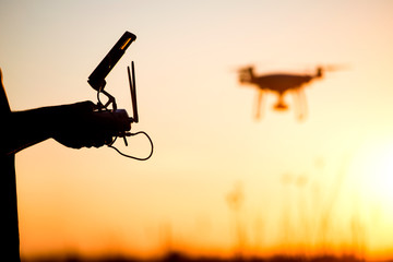 Young man operating of flying drone the setting sun