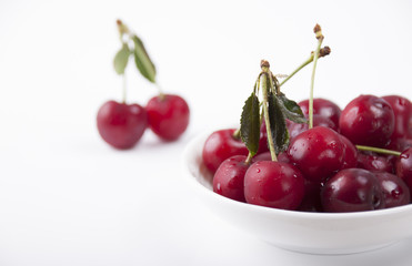 Cherries in a white plate on a white background