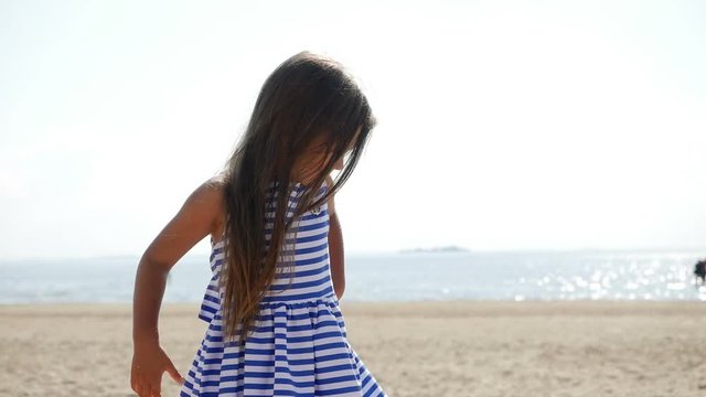 baby girl is on the beach in a striped dress