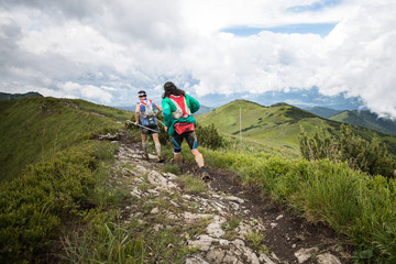Fototapeta premium two runners running together on high mountain adventure trail with epic scenery view