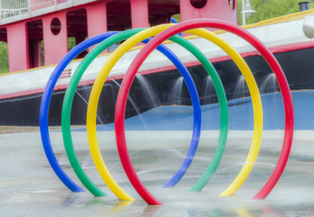 Urban park and splash pad, water spraying out of colorful rings