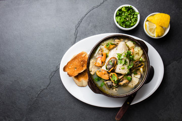 Seafood fish soup in clay bowls served with lemon and coriander. Top view, copy space