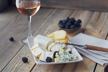 Cheese plate. Assortment of cheese with berries and glass of rose wine