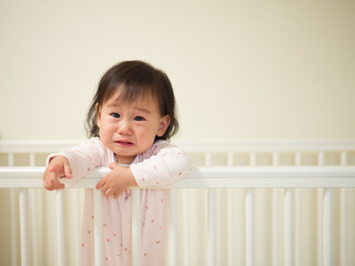 Baby girl crying in cot bed © M-image