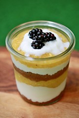 One piece of glass with dessert made of banana, mango, yogurt and blackberries
