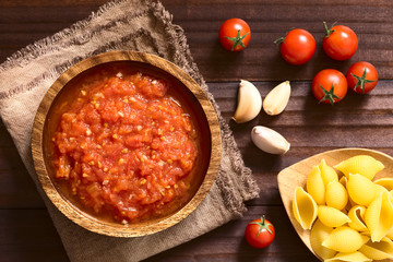 Homemade traditional Italian marinara or pomodoro tomato sauce made of fresh tomato, garlic, dried oregano and salt, photographed overhead with natural light (Selective Focus on the sauce)