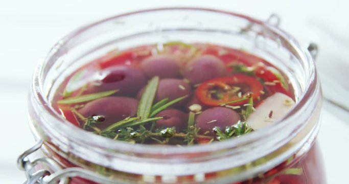 Pickled olives and herbs in a jar
