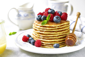 Homemade pancakes with honey and fresh berries.