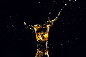 Isolated shot of whiskey with splash on black background, brandy in a glass