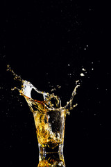 Isolated shot of whiskey with splash on black background, brandy in a glass