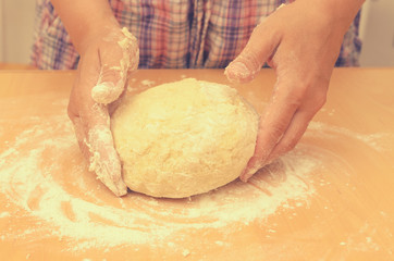 A woman kneads a homemade dough for pizza production.