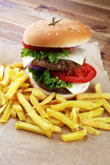 fresh tasty burger and french fries on wooden table