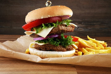 fresh tasty burger and french fries on wooden table