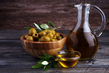 Bottle virgin olive oil and oil in a bowl with some olives