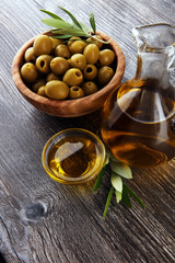 Bottle virgin olive oil and oil in a bowl with some olives