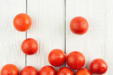 Many fresh red and ripe tomatoes scattered on old white wooden planks