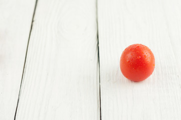 Single red tomato on rustic white wooden background