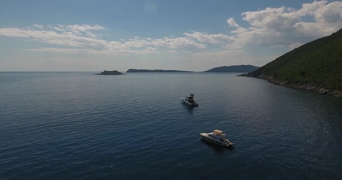Beautiful panoramic view on the Lustica peninsula from the sea beach. Flying above Janica beach and boats, sailing in the sea. Summer on the Montenegro coast