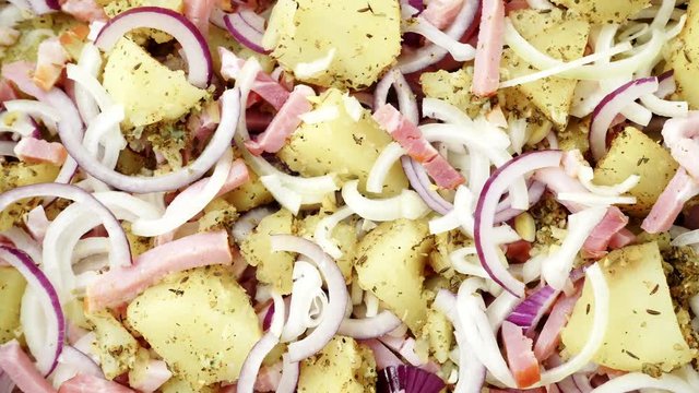 Peeled potatoes with spices, becon meat and onion slices ready to be roasted close up. Food background. Rack focus 4K ProRes HQ codec