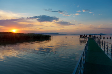 Naklejka na ściany i meble Sunset at Lake Balaton with pier and silhouettes in Hungary
