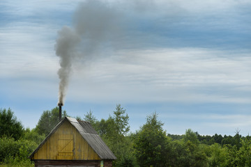 Fototapeta na wymiar kindling bath in full swing, belching black smoke from the chimney
