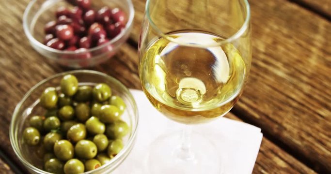 Wine served with green and red olives on wooden table