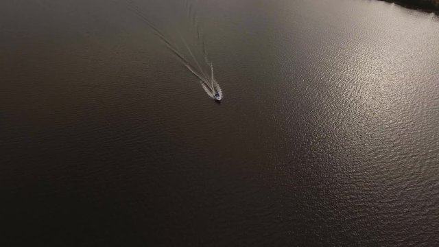 Speed boat sails on the river.Aerial view:Motor boat speeding.Fast motor boat with splash and wake.Speedboat floats on the water surface.4K,UHD. Aerial Rural landscape.