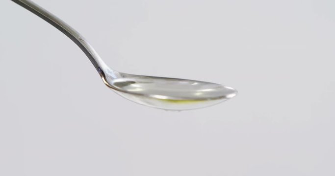Green olive falling on the spoon with olive oil