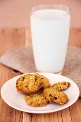 Chocolate chip cookies with milk in glass on wood table.