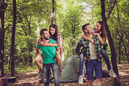So fun together! Two lovely couples, nice forest view. Guys are piggybacking their girlfriends, so happy, smiling - Powered by Adobe