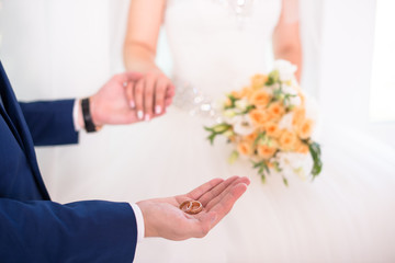Groom holding wedding rings on the palm, the groom in a blue suit, groom holding wedding rings, groom's hand holding a ring, wedding ring in groom hand