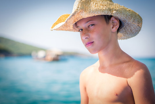 Young cute boy wearing straw hat on the beach during summer vacation