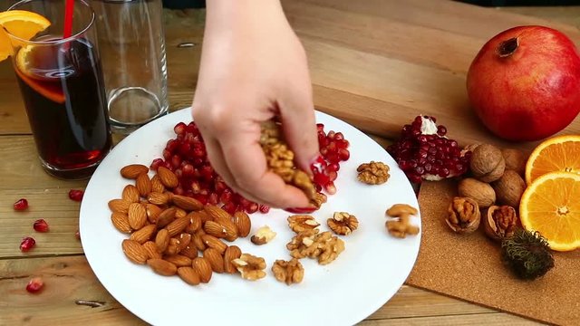 A woman with her own hands puts walnuts on a plate. Hd shot with dolly. The camera moves from left to right
