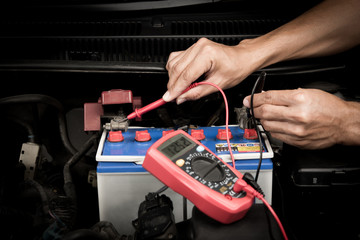 Auto technician mechanic using multimeter voltmeter check voltage level car battery