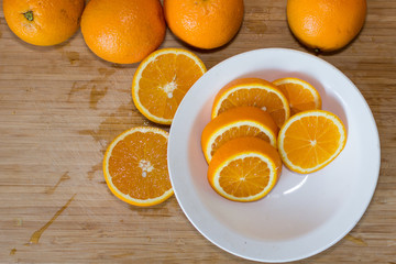 Oranges on a table and on a white plate in the kitchen