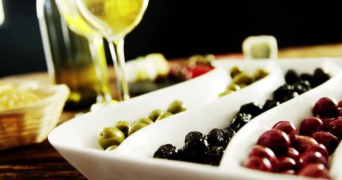 Two glasses of wine and a tray with berry fruits and olives